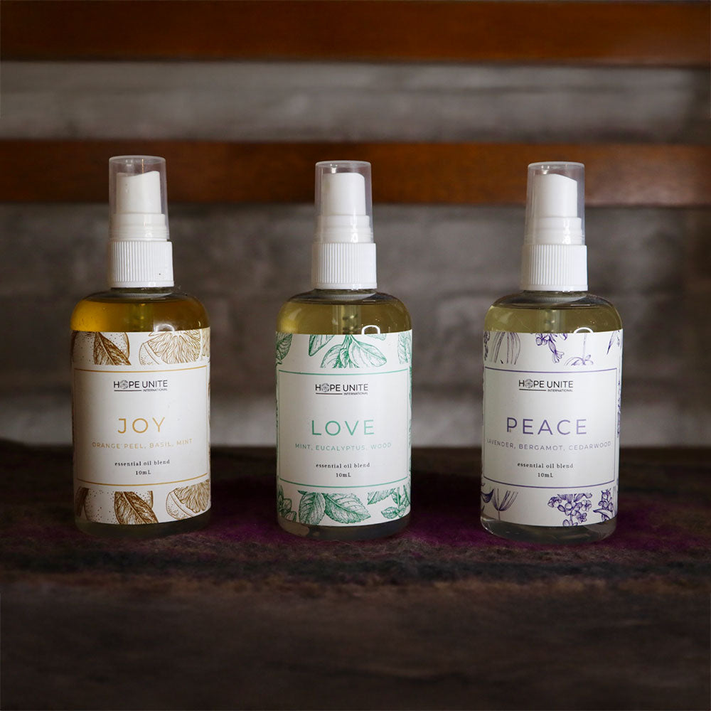 Three bottles of 'Hope Unite' products labeled 'Joy', 'Love', and 'Peace' on a wooden surface.